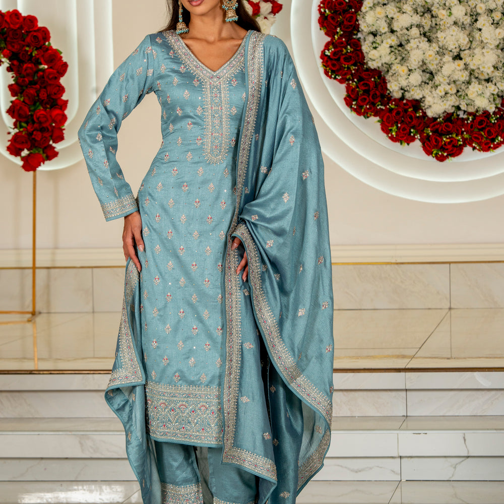 
                  
                    Woman in a light blue traditional outfit with floral decorations in the background
                  
                