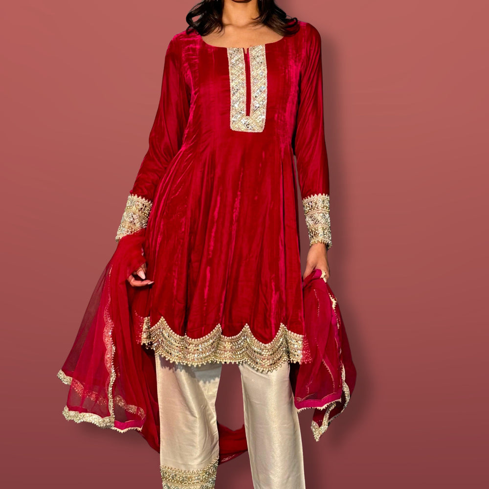 
                  
                    Woman wearing a red and white traditional outfit with Guinaz Khan branding on a maroon background.
                  
                