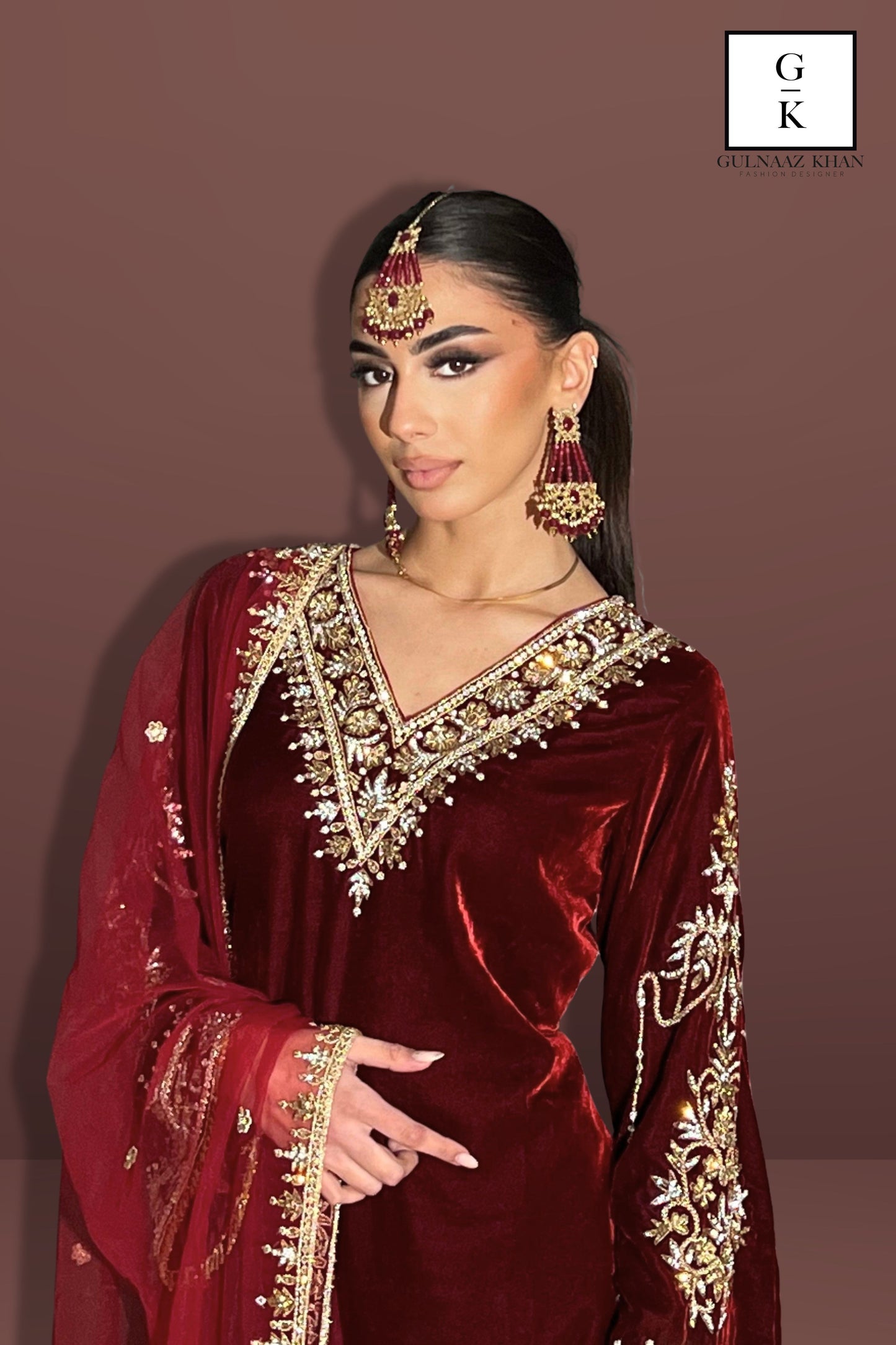 Woman wearing a red embroidered traditional outfit with gold details on a brown background
